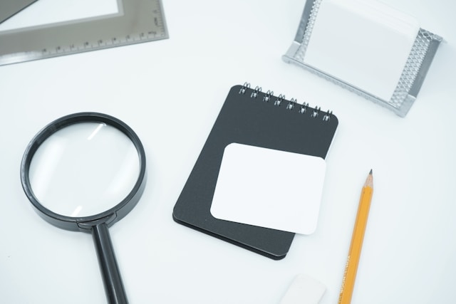 Investigation tools on a desk including a notepad and magnifying glass